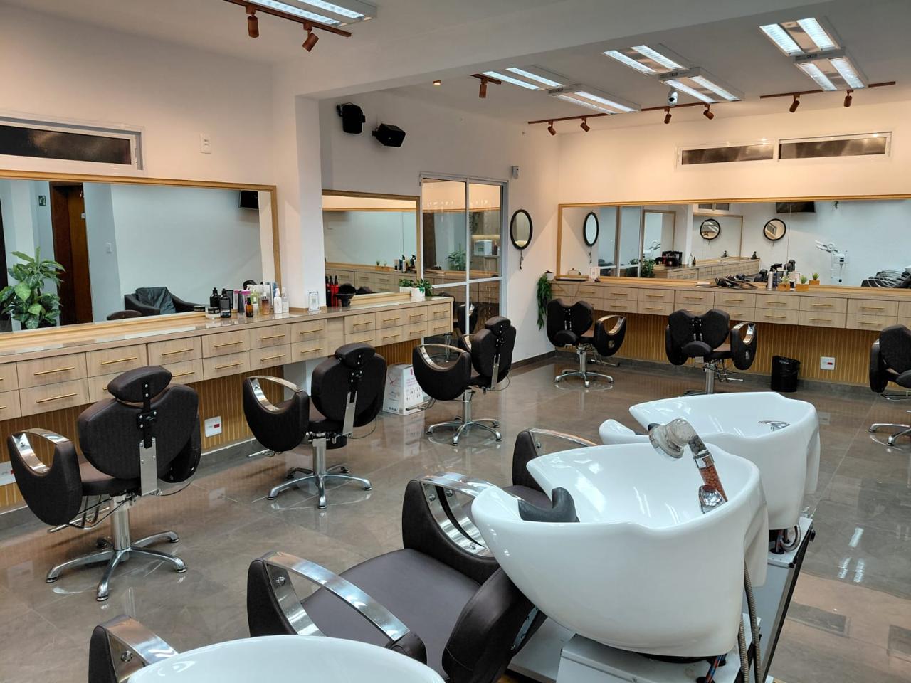 Salão de cabelo com bancadas, espelhos e lavatórios