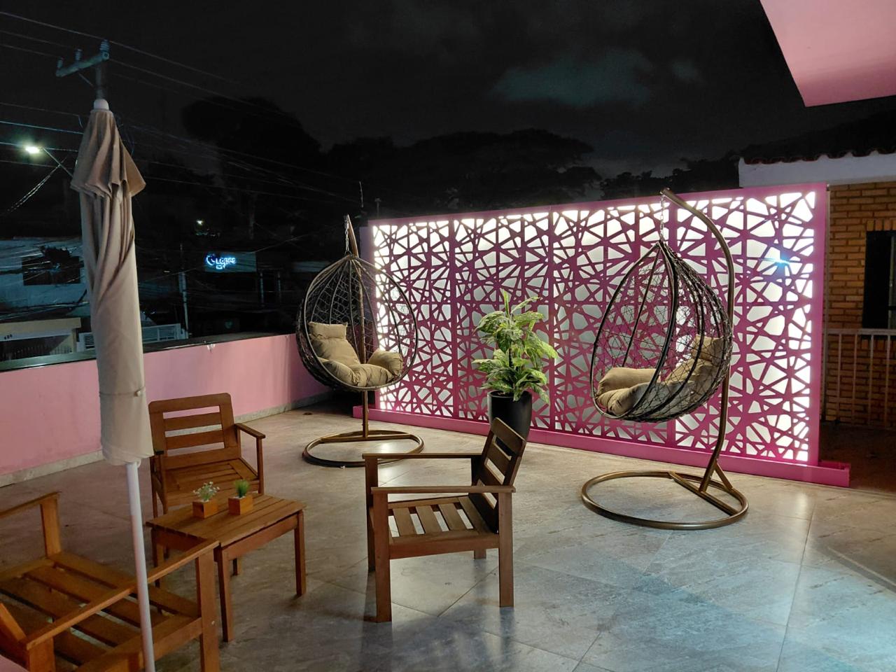 Terraço iluminado com cadeiras suspensas e poltronas de madeira